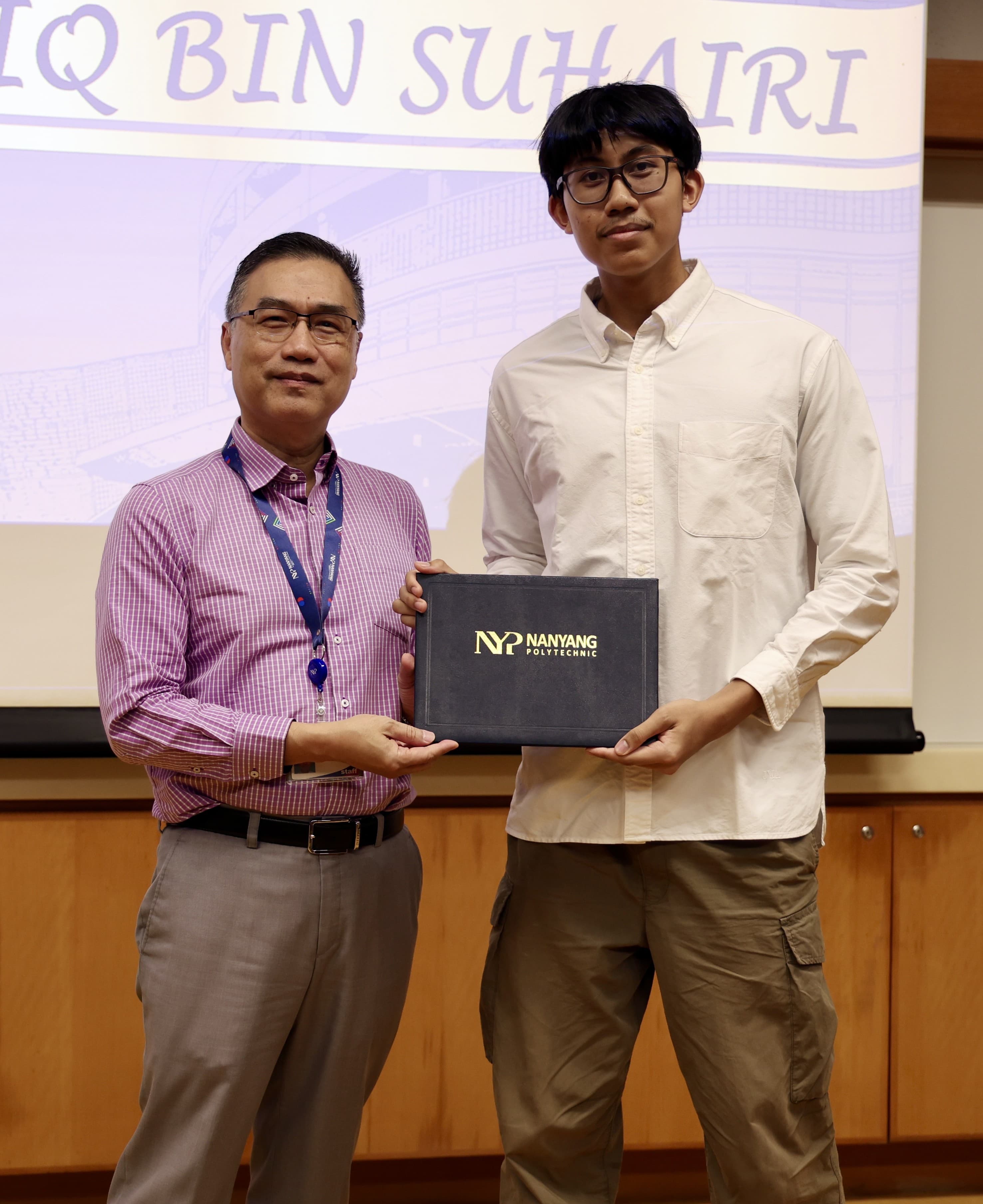 Muhammad Sadiq receiving an award folder from a Nanyang Polytechnic staff member at an award ceremony