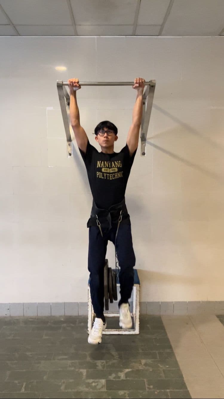 Muhammad Sadiq performing a weighted pull-up during calisthenics training